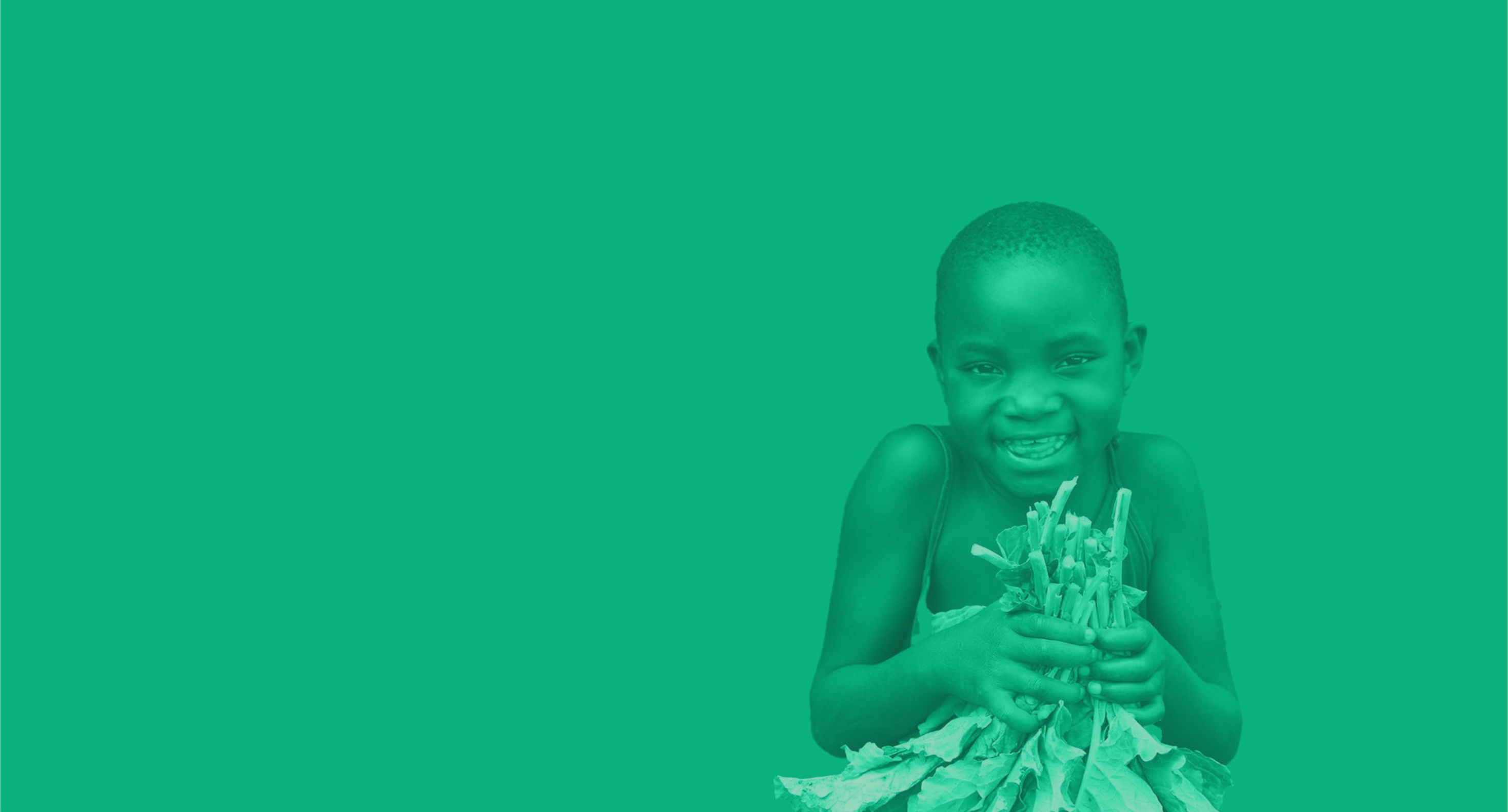 Child holding plants against a green background